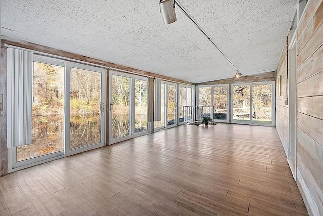 unfurnished sunroom featuring track lighting and lofted ceiling