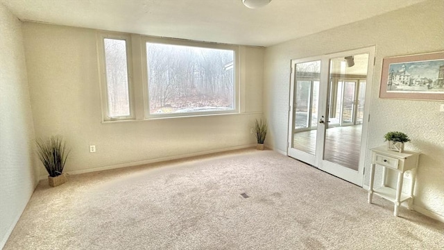 empty room featuring plenty of natural light, light colored carpet, and french doors