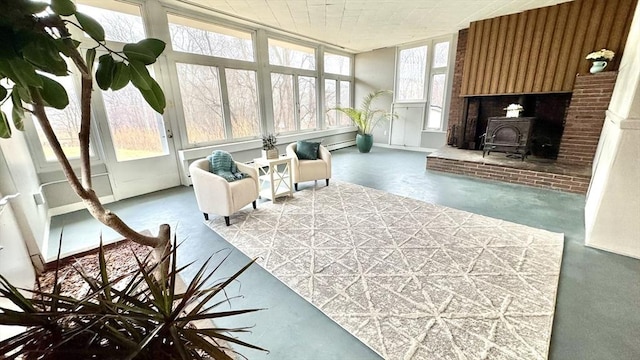 sunroom with a wood stove and a baseboard heating unit