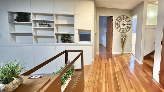 hallway with built in shelves and light hardwood / wood-style flooring