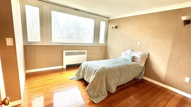 bedroom with hardwood / wood-style flooring, radiator, and ornamental molding