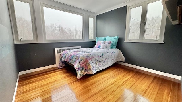 bedroom featuring radiator heating unit and light hardwood / wood-style flooring