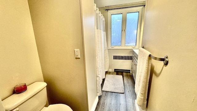 bathroom featuring toilet, wood-type flooring, and radiator heating unit