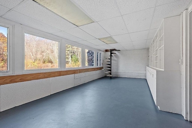 unfurnished sunroom with a drop ceiling and a wealth of natural light