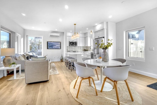 dining room featuring light wood-type flooring, baseboards, and an AC wall unit