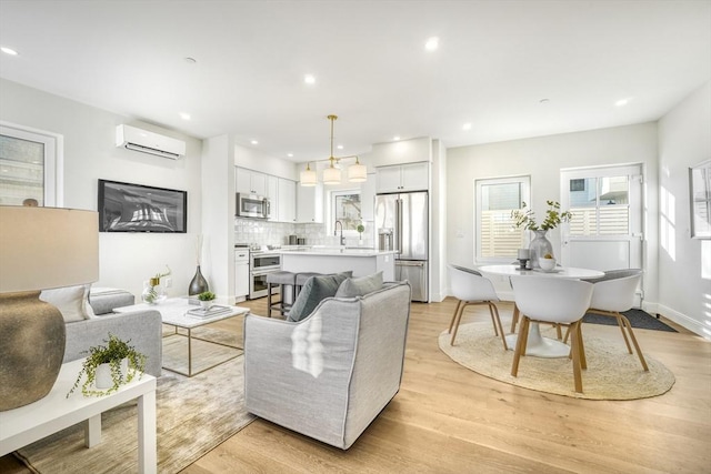 living room with a wall unit AC, light wood-type flooring, baseboards, and recessed lighting