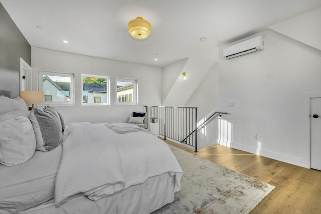 bedroom featuring baseboards, a wall mounted AC, wood finished floors, and recessed lighting