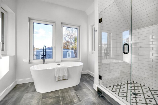 bathroom with a stall shower, a freestanding tub, and baseboards