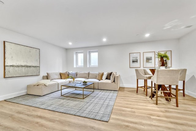 living room featuring light wood finished floors, baseboards, and recessed lighting