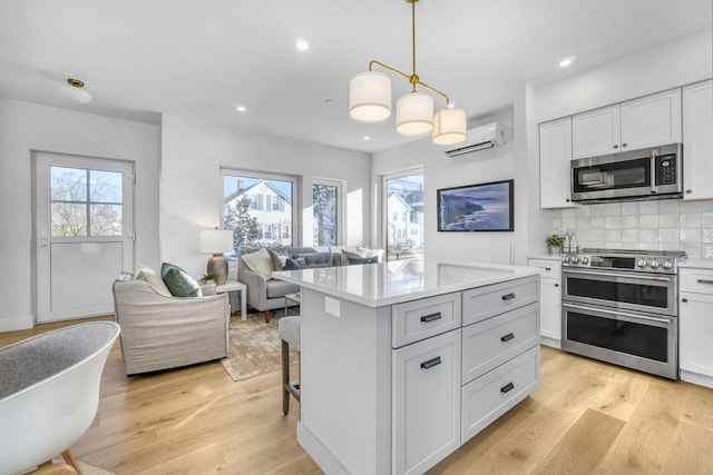 kitchen featuring pendant lighting, stainless steel appliances, light countertops, open floor plan, and white cabinetry