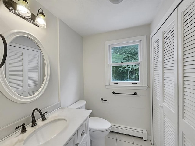 bathroom with a closet, toilet, baseboard heating, vanity, and tile patterned floors