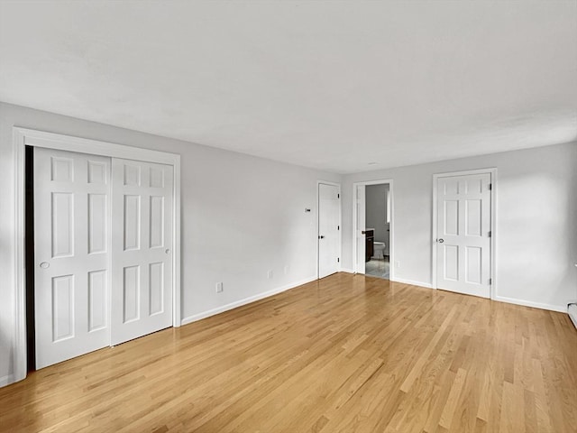 unfurnished bedroom featuring multiple closets, light wood-type flooring, and baseboards