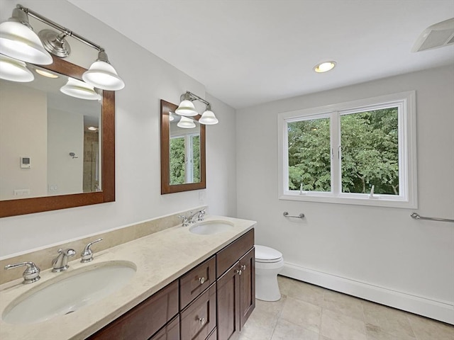 bathroom featuring toilet, a sink, baseboard heating, and double vanity