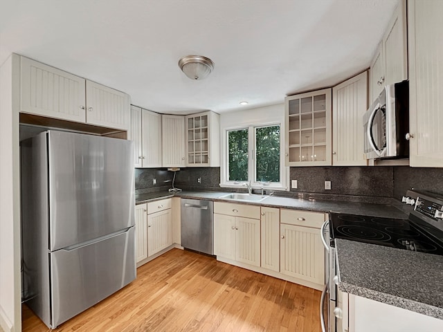 kitchen with sink, stainless steel appliances, tasteful backsplash, and light hardwood / wood-style flooring