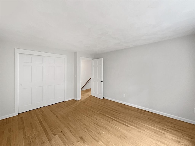 unfurnished bedroom with light wood-style floors, baseboards, and a closet