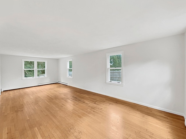 empty room with light hardwood / wood-style floors and a baseboard heating unit