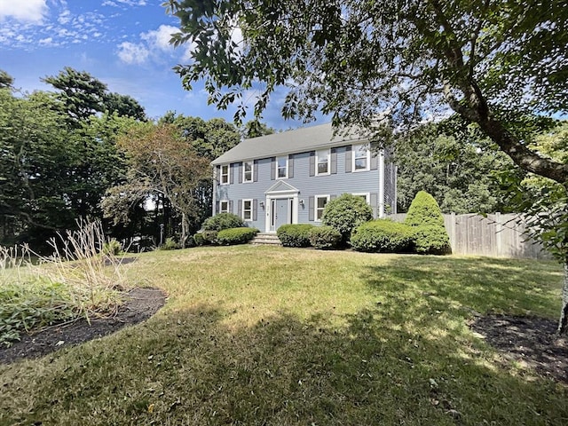 colonial inspired home with fence and a front yard