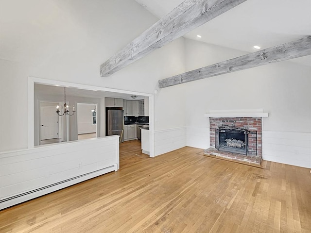 unfurnished living room featuring light wood-style floors, a baseboard radiator, beamed ceiling, and a wainscoted wall