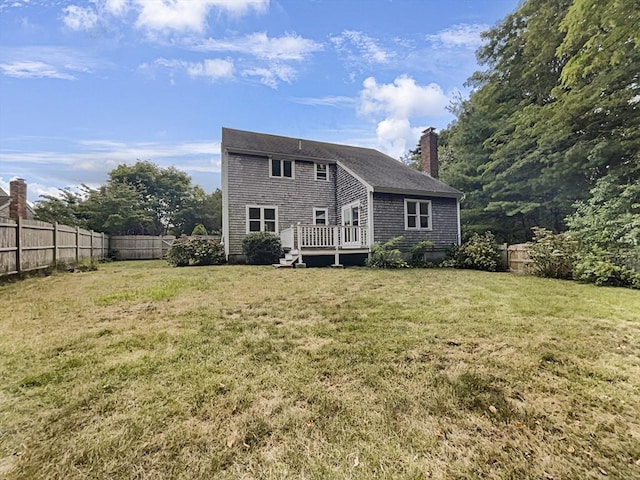 rear view of property featuring a fenced backyard, a lawn, and a wooden deck