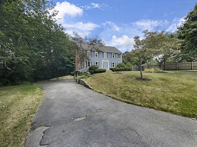 colonial house with driveway, a front lawn, and fence