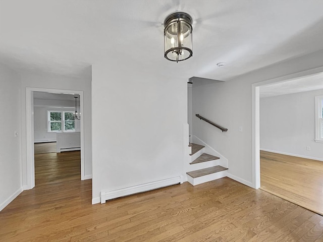 interior space with a baseboard heating unit, an inviting chandelier, and wood finished floors