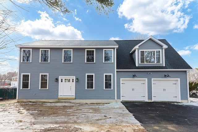 colonial home featuring aphalt driveway, a shingled roof, and a garage