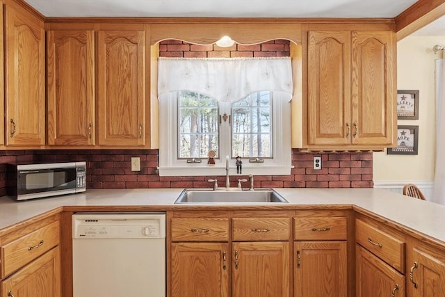 kitchen featuring light countertops, white dishwasher, backsplash, and a sink