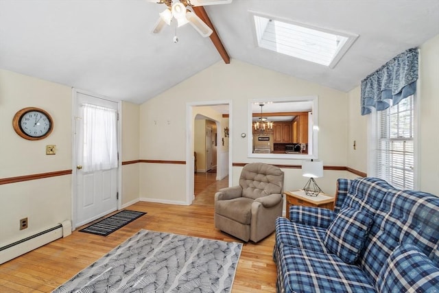 living area featuring vaulted ceiling with skylight, a baseboard heating unit, ceiling fan with notable chandelier, baseboards, and light wood-style floors