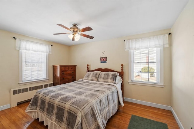 bedroom with radiator heating unit, baseboards, ceiling fan, and wood finished floors