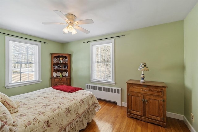 bedroom with baseboards, light wood finished floors, a ceiling fan, and radiator