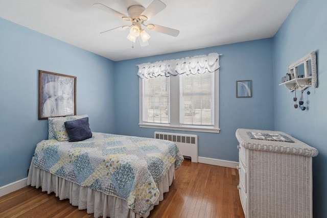 bedroom with radiator, wood-type flooring, baseboards, and a ceiling fan