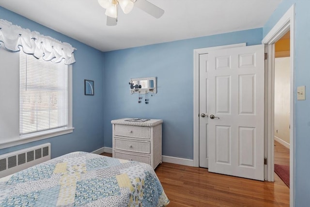 bedroom with baseboards, ceiling fan, wood finished floors, and radiator