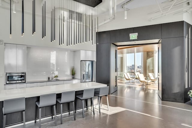 kitchen featuring concrete flooring, sink, a kitchen bar, decorative backsplash, and stainless steel appliances