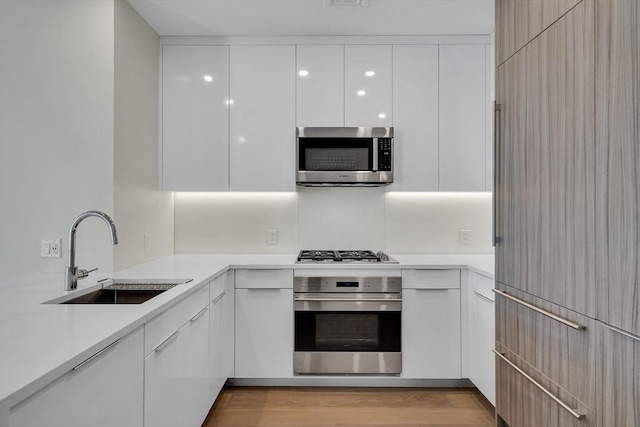 kitchen with sink, stainless steel appliances, light hardwood / wood-style floors, and white cabinets