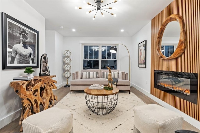 living area with a glass covered fireplace, a notable chandelier, wood finished floors, and recessed lighting