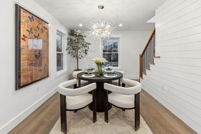 dining space with baseboards, an inviting chandelier, stairs, and light wood finished floors