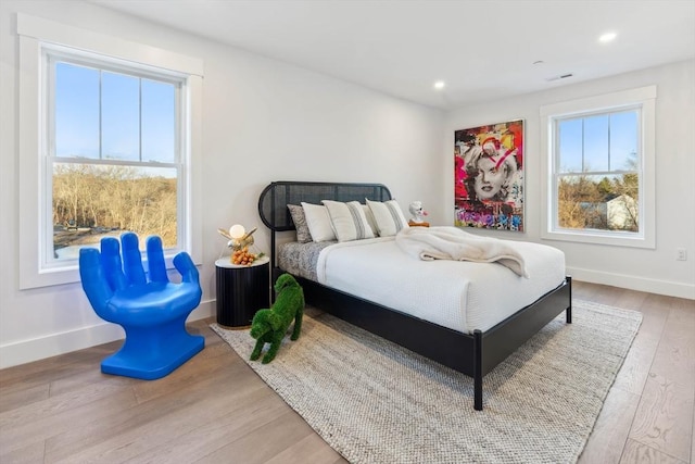 bedroom with multiple windows, baseboards, and wood finished floors