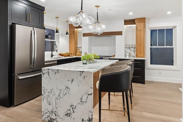 kitchen with pendant lighting, light wood-type flooring, freestanding refrigerator, and a kitchen island