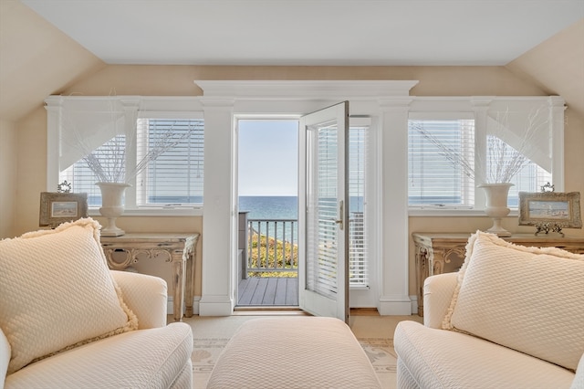 living area featuring a water view, lofted ceiling, light colored carpet, and a wealth of natural light