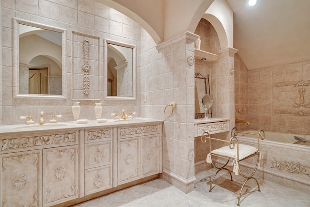 bathroom with tiled tub, vanity, tile walls, and vaulted ceiling