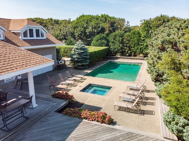 view of swimming pool featuring a wooden deck, an in ground hot tub, and a patio area