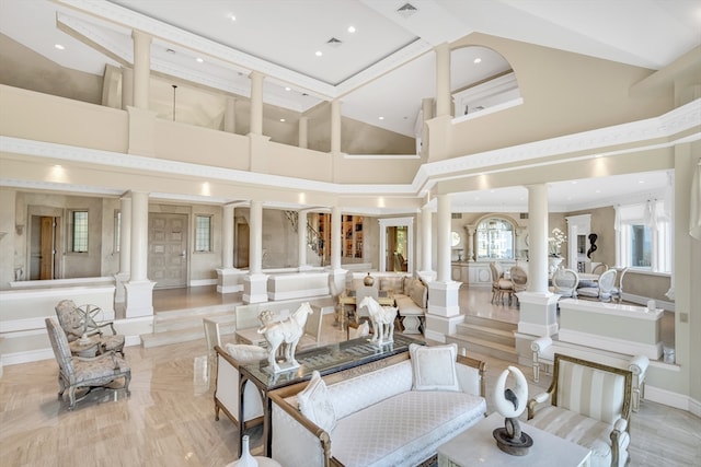 living room featuring light wood-type flooring, decorative columns, and a high ceiling