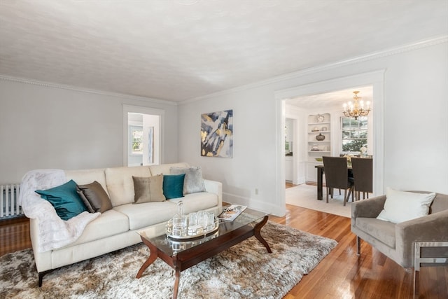 living room with an inviting chandelier, wood-type flooring, built in features, ornamental molding, and a textured ceiling