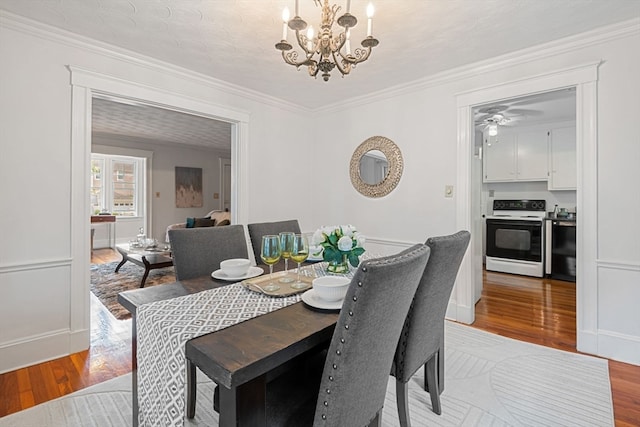 dining room featuring ceiling fan with notable chandelier, light hardwood / wood-style floors, and crown molding