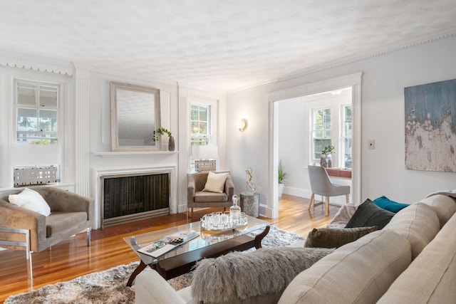 living room featuring ornamental molding, light hardwood / wood-style floors, and a textured ceiling