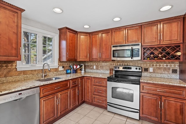 kitchen featuring appliances with stainless steel finishes, tasteful backsplash, light stone countertops, a sink, and light tile patterned floors