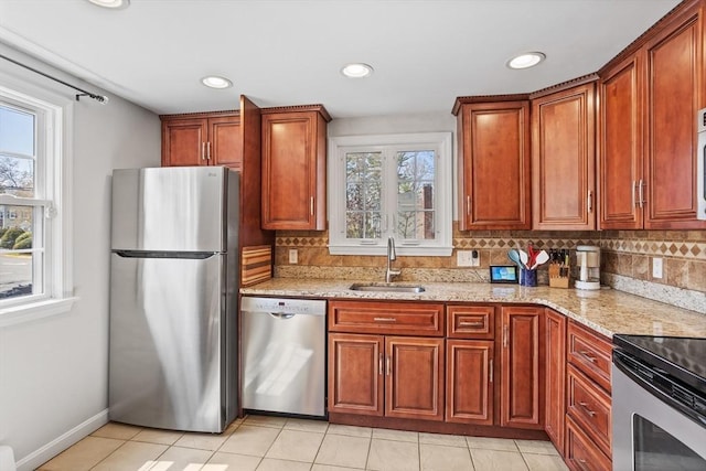 kitchen featuring backsplash, appliances with stainless steel finishes, light stone countertops, a sink, and light tile patterned floors