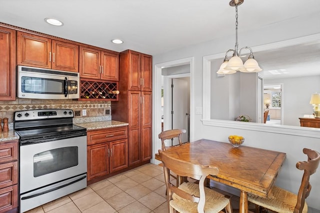 kitchen with backsplash, light tile patterned floors, hanging light fixtures, and stainless steel appliances