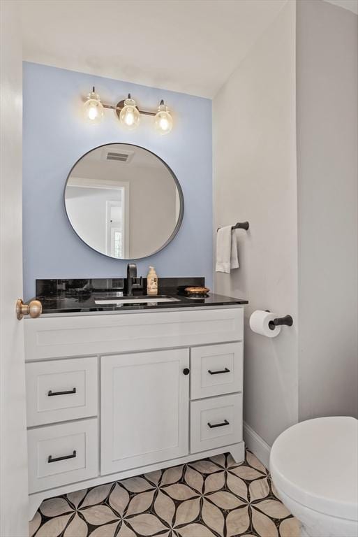 bathroom with vanity, baseboards, toilet, and visible vents