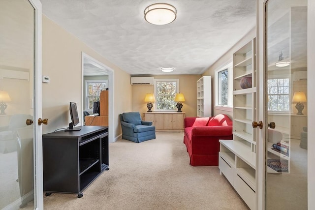 sitting room featuring light carpet, a wall mounted air conditioner, a textured ceiling, french doors, and baseboards